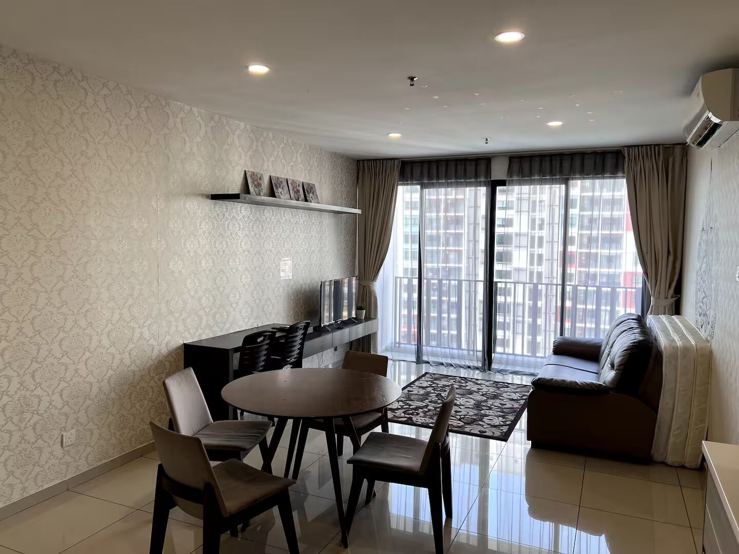 A modern living room with a dining area, a sofa, and a TV on a shelf.