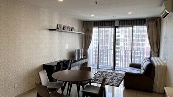 A modern living room with a dining area, a sofa, and a TV on a shelf.