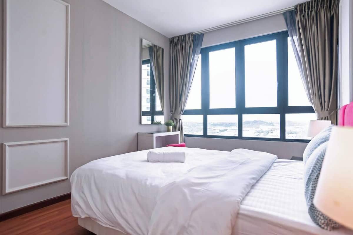 Habitación de hotel con una cama grande, un escritorio, una silla, un ventanal con cortinas y vistas a un paisaje nevado.