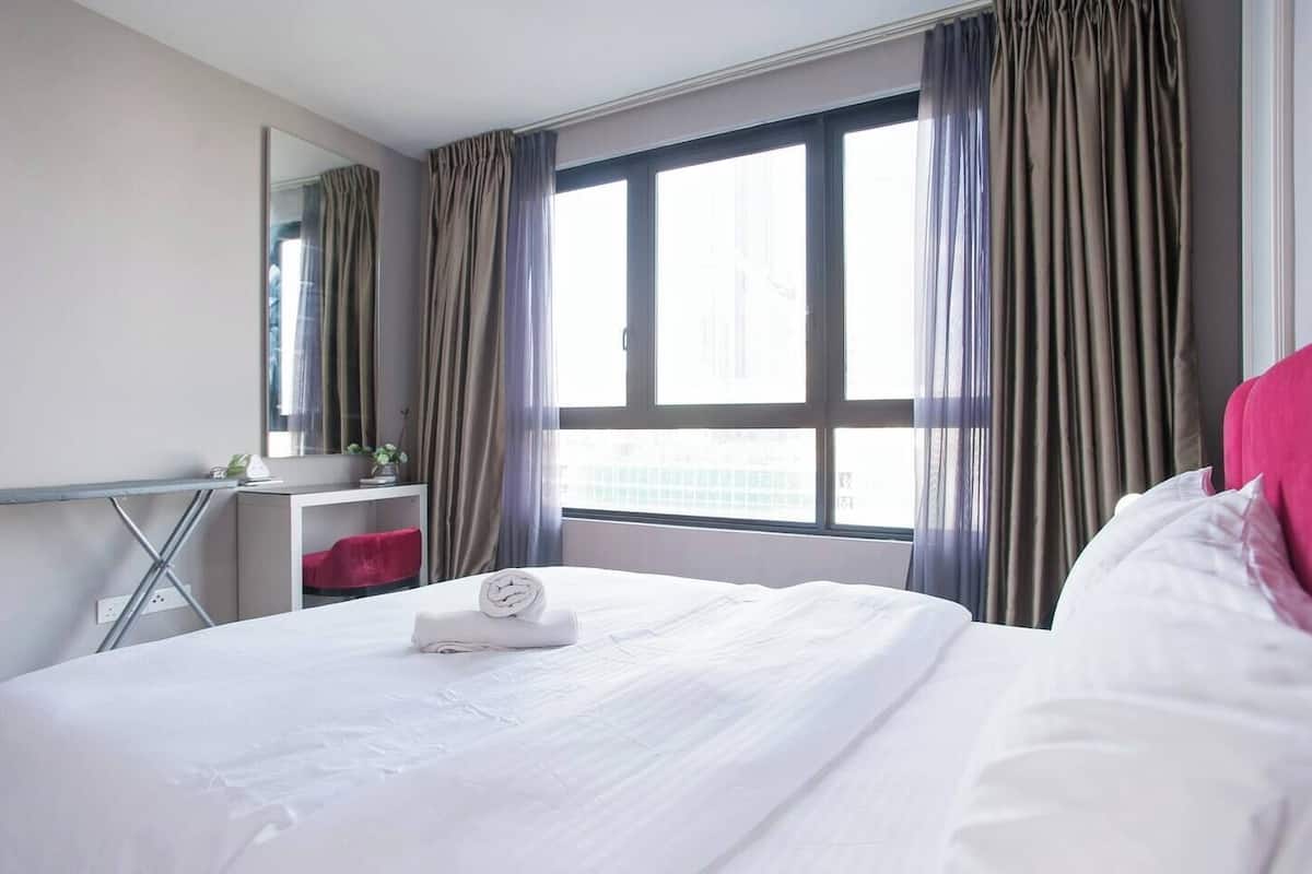 Una habitación de hotel con una cama grande, un escritorio y una ventana con cortinas.