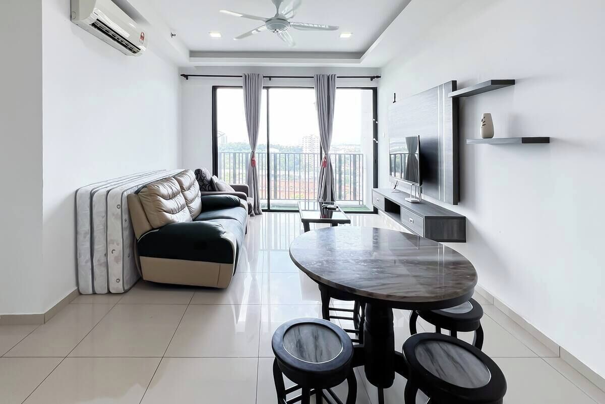 Una sala de estar moderna con un sofá, una mesa de comedor con taburetes, un televisor de pantalla plana y un balcón con cortinas.