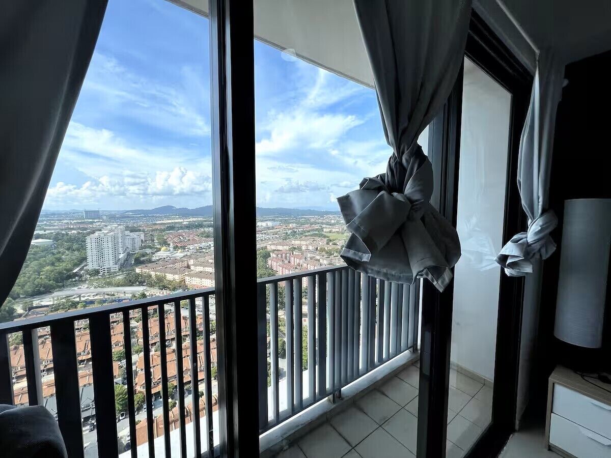 Un balcón con vista a un paisaje urbano, un ventanal grande y una cortina.