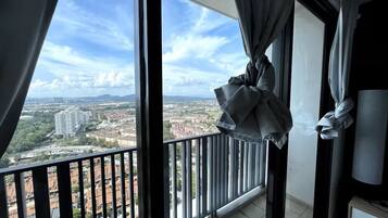 Un balcón con vista a un paisaje urbano, un ventanal grande y una cortina.