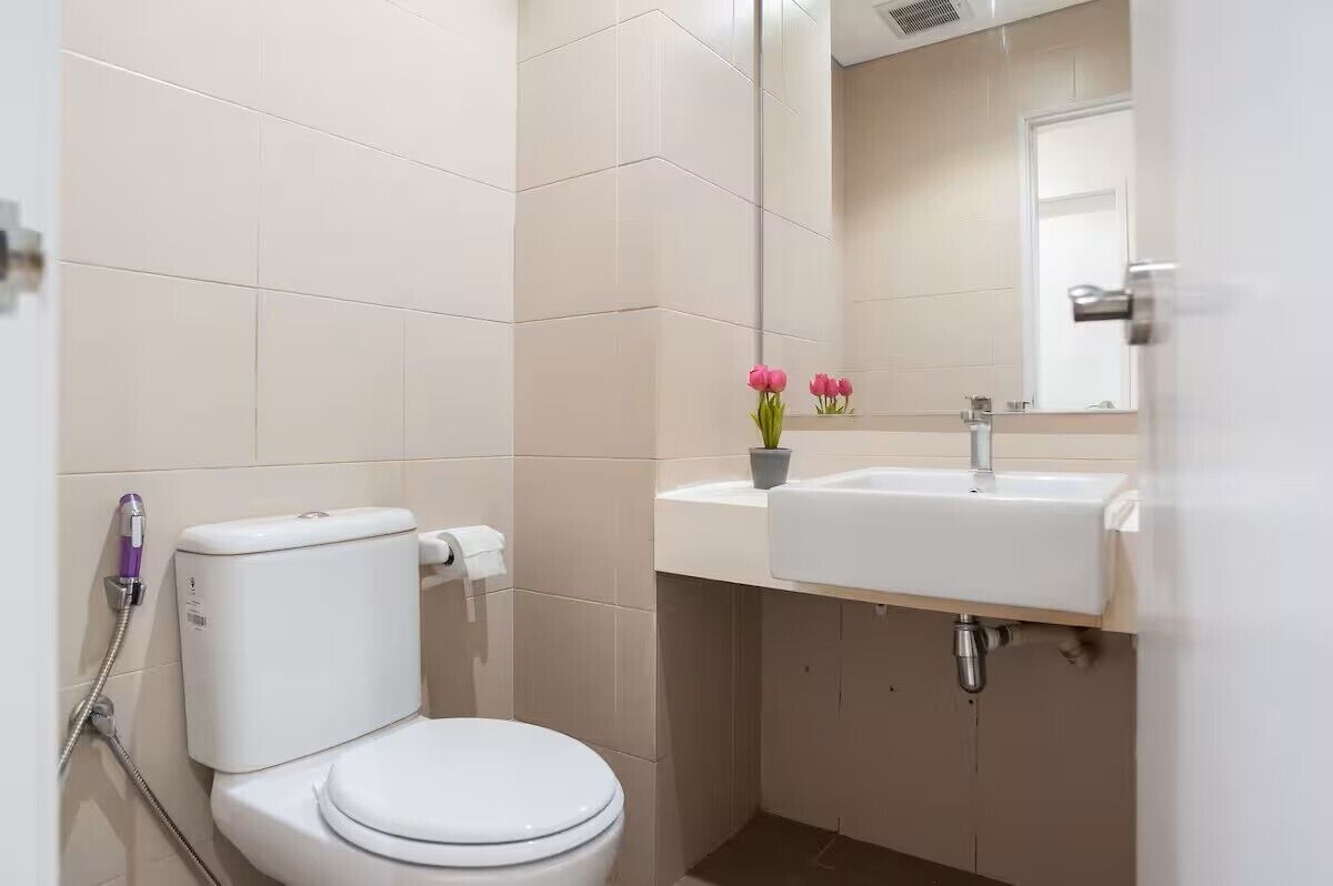 A bathroom with a toilet, sink, and mirror.