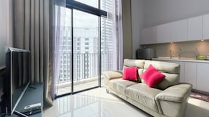 A modern living room with a sofa, a flat-screen TV, and a sliding glass door leading to a balcony.