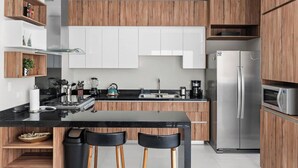 Una cocina moderna con armarios de madera, un refrigerador de acero inoxidable, un microondas y una encimera negra.