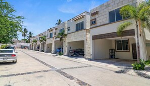 A residential street with modern houses, parked cars, and palm trees. - Family Villa Near Beach with Pool + Parking (Bucerías)