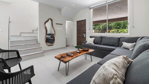 A modern living room with a sofa, a coffee table, and a staircase.