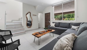 A modern living room with a sofa, a coffee table, and a staircase.
