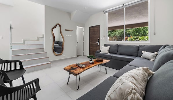 A modern living room with a sofa, a coffee table, and a staircase.