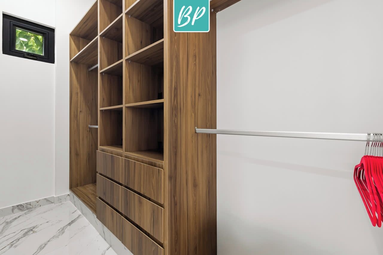 A wooden wardrobe with multiple shelves, a metal rod for hanging items, and a small window.