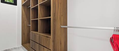 A wooden wardrobe with multiple shelves, a metal rod for hanging items, and a small window.
