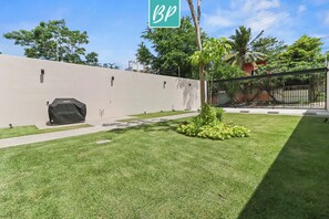 A well-maintained outdoor area with a paved walkway, a covered grill, and a small garden with a palm tree. - 2BR w/ Pool, Fast WiFi & Beach Gear - Stanza 7 (Bucerías)