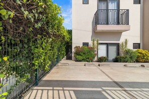 A modern building with a balcony, a concrete pathway, and a green hedge. - 2BR w/ Pool, Fast WiFi & Beach Gear - Stanza 7 (Bucerías)