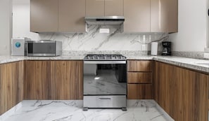 A modern kitchen with wooden cabinets, a stainless steel stove, a microwave, and a coffee maker. - 2BR w/ Pool, Fast WiFi & Beach Gear - Stanza 7 (Bucerías)