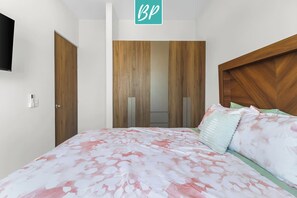 A bedroom with a bed, a wardrobe, a television, and a door. - 2BR Near Beach w Shared Pool & Beach Gear: Stanza 11 (Bucerías)