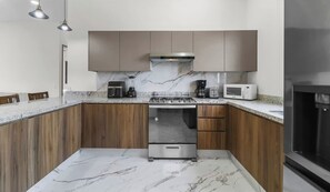 Une cuisine moderne avec des meubles en bois, une cuisinière en acier inoxydable et un plan de travail en marbre.