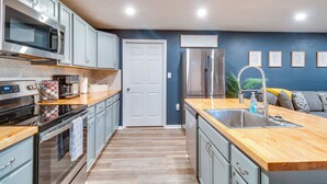 A modern kitchen with stainless steel appliances, light blue cabinets, a wooden countertop, and a built-in sink. - 7 Mi to Lake Tangipahoa: McComb Home w/ Deck! (McComb)