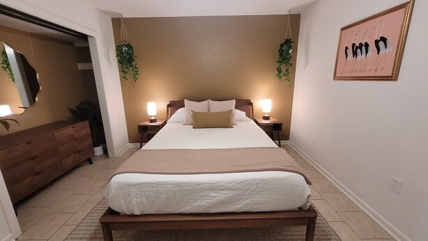 A bedroom with a bed, bedside tables, a dresser, and a mirror. - Mid City Modern, Good Vibes in BRLA (Baton Rouge)