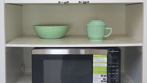 A kitchen with a microwave, green bowls, and a salt and pepper shaker on the shelves. - Mid City Modern, Good Vibes in BRLA (Baton Rouge)
