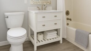 A bathroom with a toilet, sink, mirror, shower, and a towel rack. - Bright Studio Retreat in Chico (Chico)