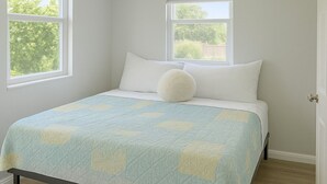 A bedroom with a bed, two windows, and a view of trees. - Bright Studio Retreat in Chico (Chico)