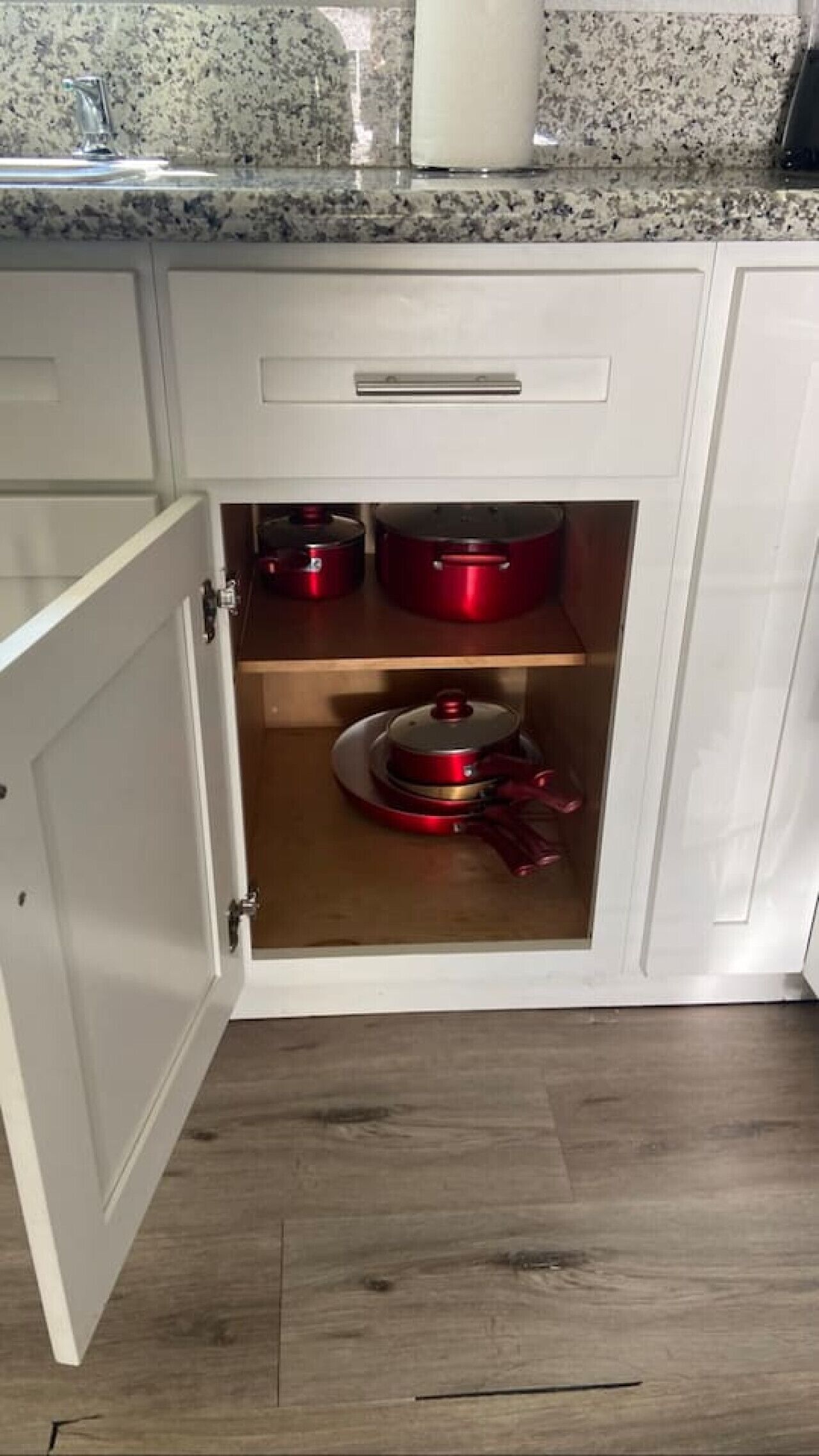 Keittiössä on valkoiset kaapit, graniittitaso ja puulattia.