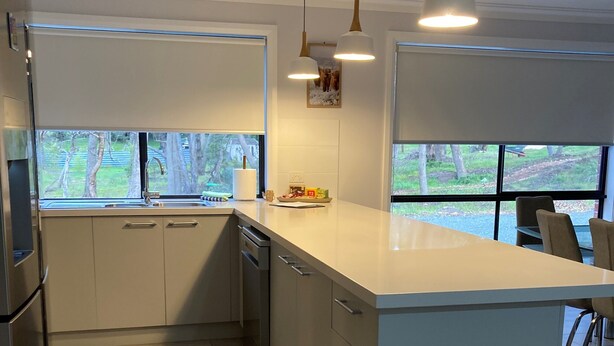 A modern kitchen with a large island, stainless steel appliances, and large windows offering views of the outdoors. - Country Retreat (Beaufort)