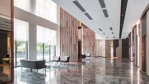 Eine großzügige Lobby mit einem glänzenden Marmorboden, großen Fenstern und moderner Möblierung.