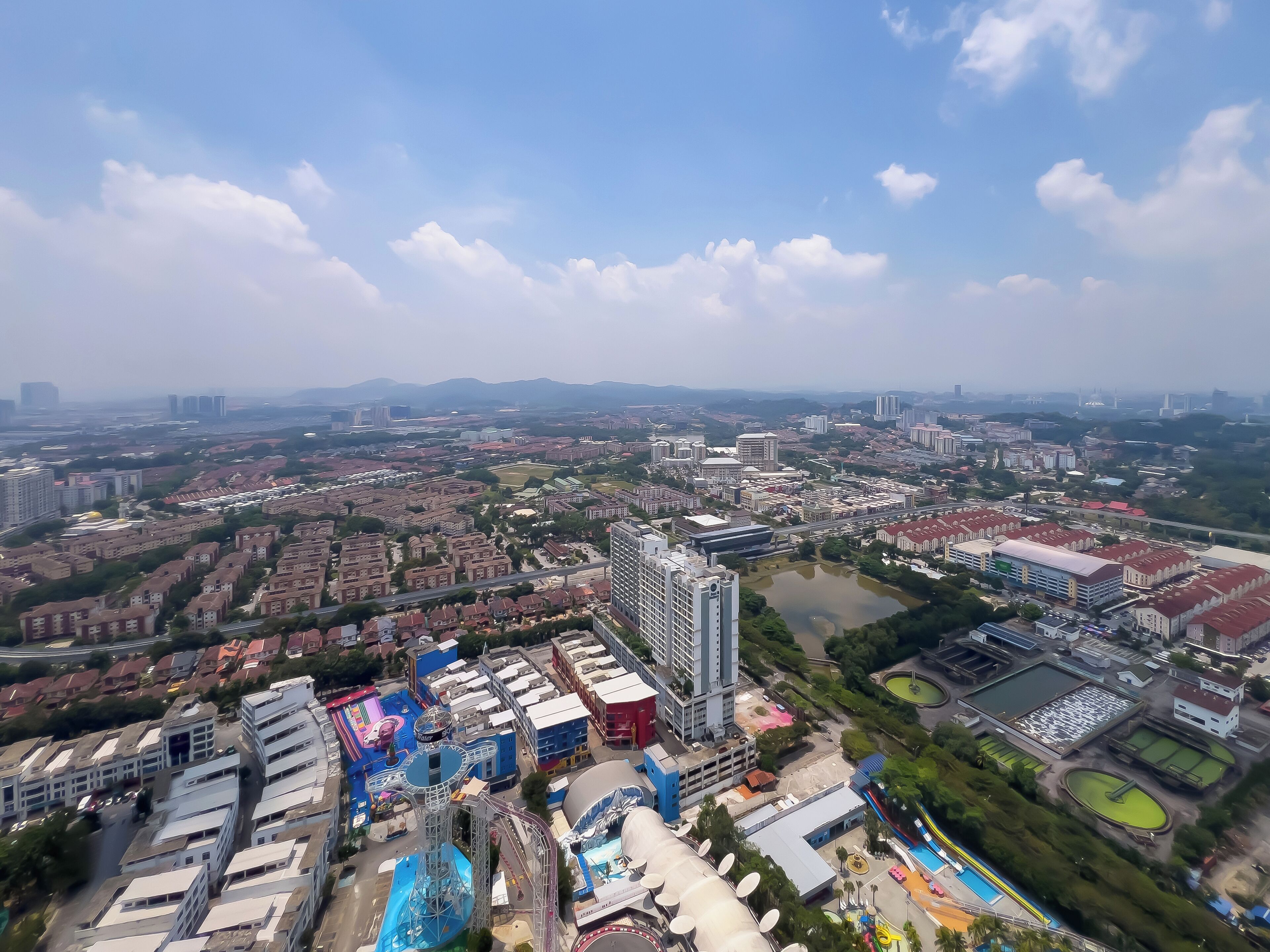 An aerial view of a cityscape with residential buildings, a large water park, and a stadium.