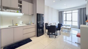 Eine moderne Küche mit integriertem Kühlschrank, einer Essecke mit Tisch und Stühlen sowie einem großen Fenster für natürliches Licht.