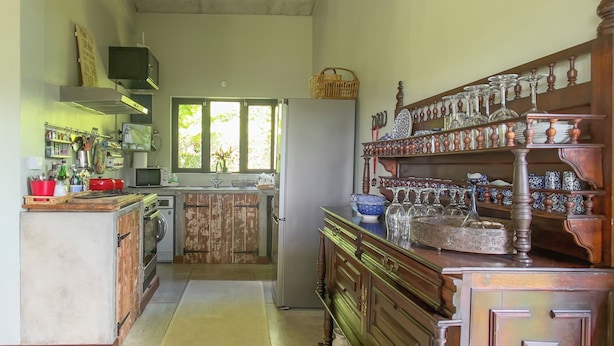 A kitchen with wooden cabinets, a refrigerator, and a window. - Green Cottage Chamarel (Chamarel)