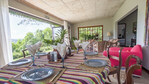 A dining area with a table set for four, featuring striped tablecloths and blue patterned plates. - Green Cottage Chamarel (Chamarel)