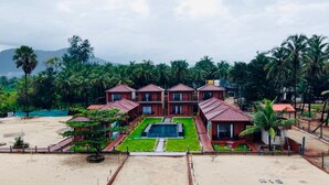Un resort con varias edificaciones tipo bungalow, una piscina y abundante vegetación.