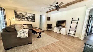 A living room with a sofa, coffee table, and TV stand. - Peaceful Country Retreat (Webster)