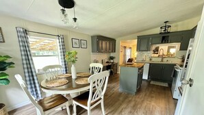 A spacious kitchen with a dining area, featuring a wooden table, white chairs, and a central island. - Peaceful Country Retreat (Webster)