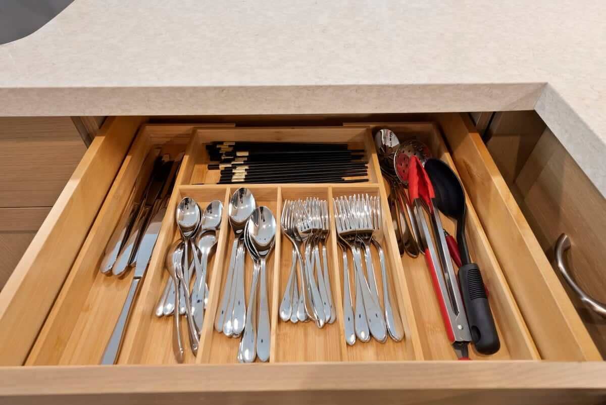 A drawer with neatly organized silverware, including forks, spoons, and knives.