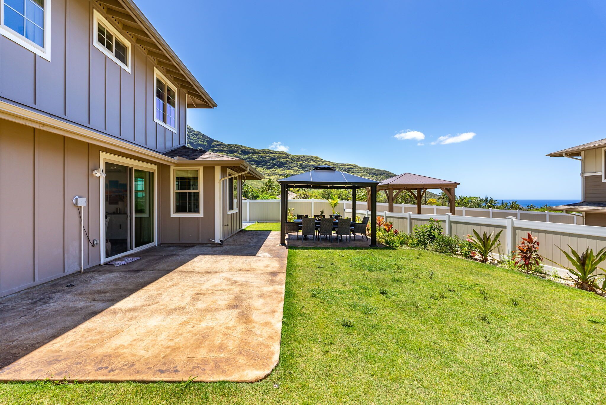 A house with a covered patio, a lawn, and a view of the ocean.