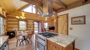 L’intérieur d’une cabane en rondins comprend un coin repas, une cuisine et une cheminée.