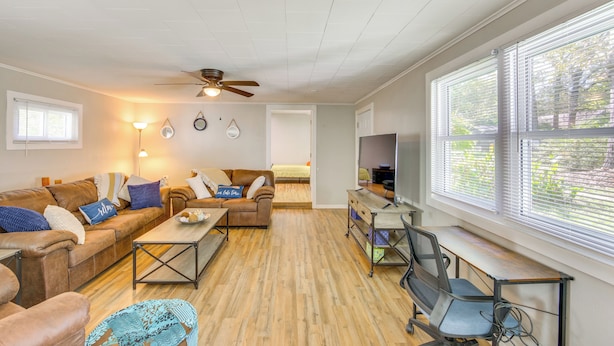 A spacious living room with a brown leather sofa, a wooden coffee table, and a TV on a stand. - < 1 Mi to Lake: Secluded Ore City Getaway (Ore City)