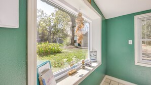 A room with a large window overlooking a garden, a small table with a notebook, and a decorative hanging light. - < 1 Mi to Lake: Secluded Ore City Getaway (Ore City)