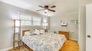 A bedroom with a bed, a ceiling fan, a window with blinds, a bedside table, and a wall-mounted air conditioner. - < 1 Mi to Lake: Secluded Ore City Getaway (Ore City)