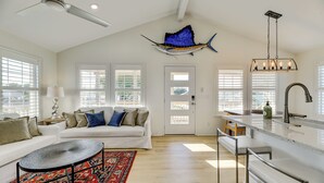 A spacious living area with a white sofa, a coffee table, and a red patterned rug.