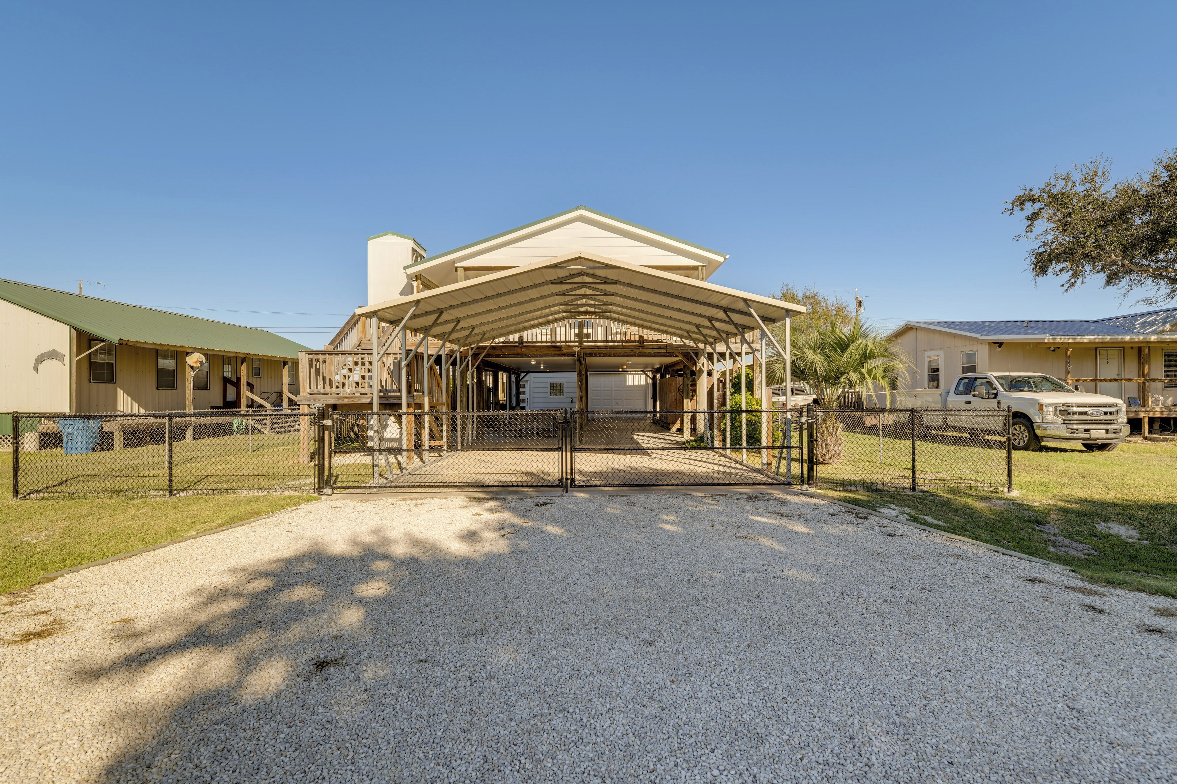 A covered outdoor area with a gravel driveway leading to a building with a green roof.