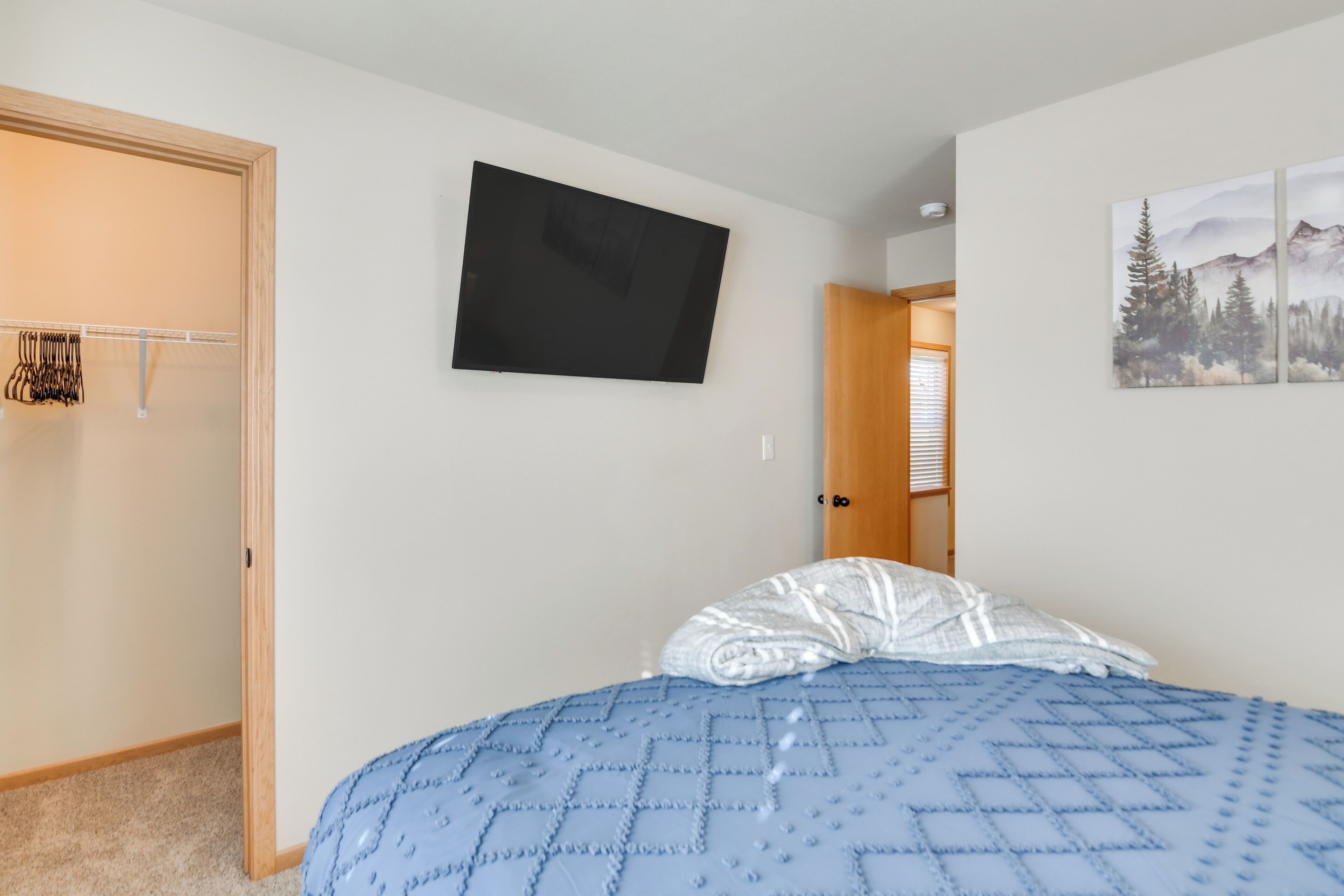 Une chambre à coucher comprenant un lit, une armoire, un téléviseur à écran plat et une porte donnant sur une autre pièce.
