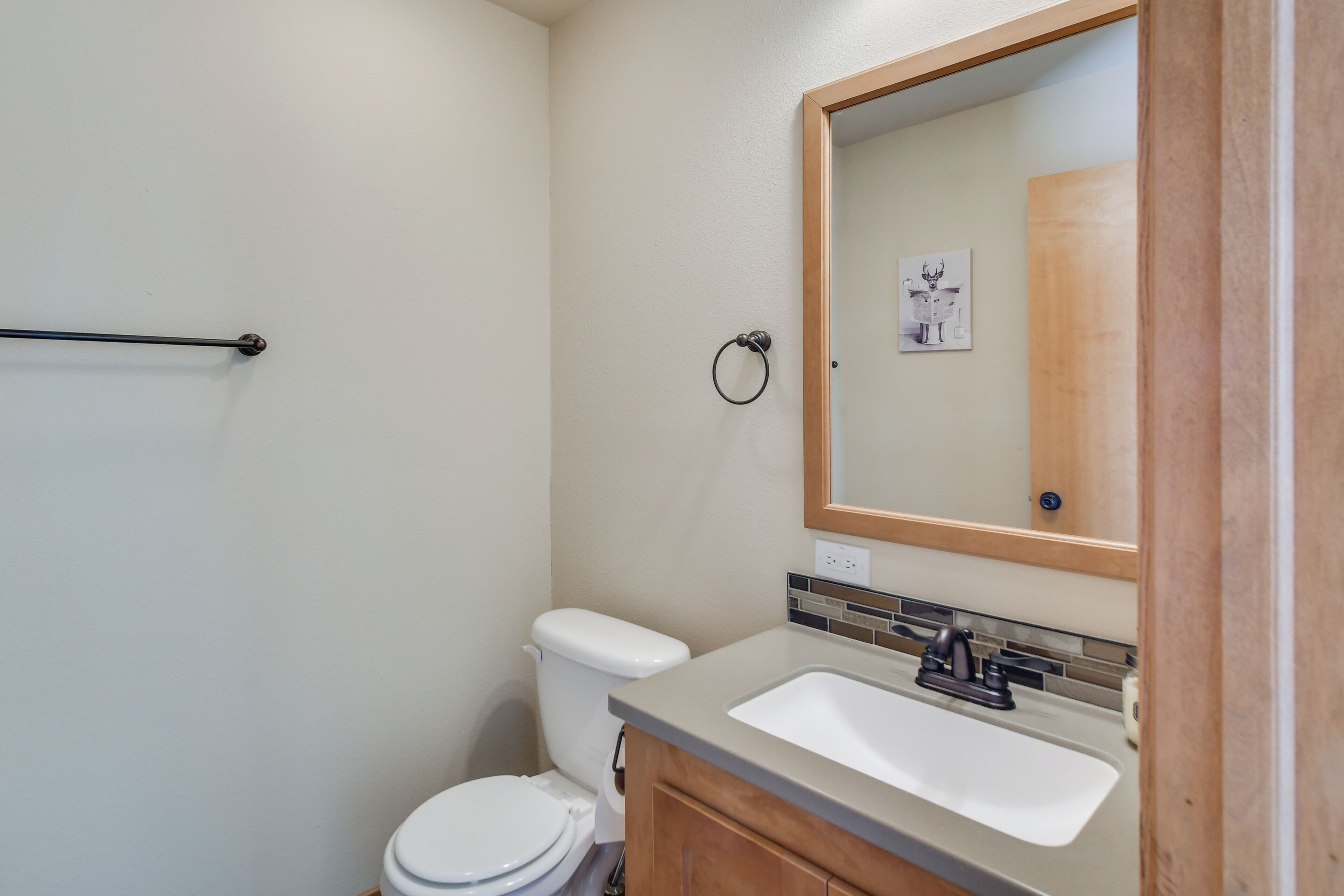 A bathroom with a white toilet, a sink with a mirror above it, and a towel rack.