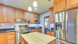A modern kitchen with wooden cabinets, stainless steel appliances, and a central island. - Spacious Home w/ Hot Tub in Fort Walton Beach! (Fort Walton Beach)