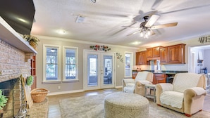 A spacious living room with a fireplace, comfortable seating, and a kitchen area in the background. - Spacious Home w/ Hot Tub in Fort Walton Beach! (Fort Walton Beach)