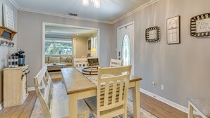 A dining area with a wooden table and chairs, a kitchen area with a coffee machine, and a living room with a sofa and a window. - Spacious Home w/ Hot Tub in Fort Walton Beach! (Fort Walton Beach)