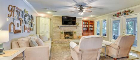 A living room with a fireplace, a ceiling fan, and a bookshelf.